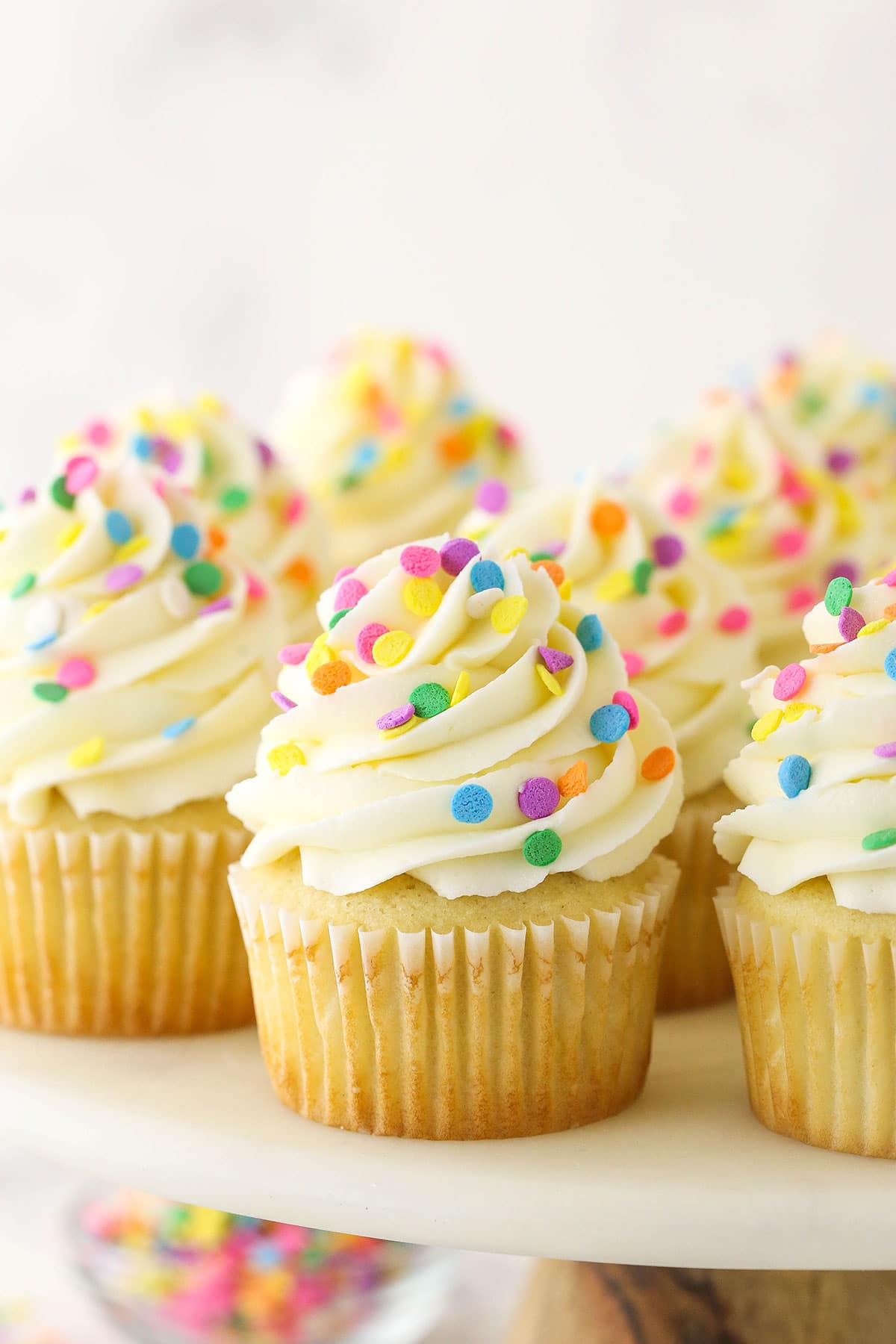 vanilla cupcakes with multicolored sprinkles on marble stand