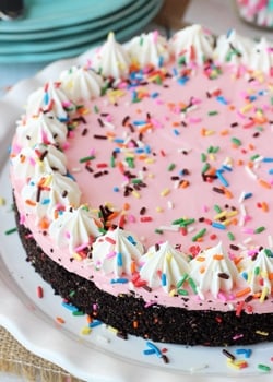 Overhead view of a full No Bake Strawberry Milkshake Cheesecake on a white platter