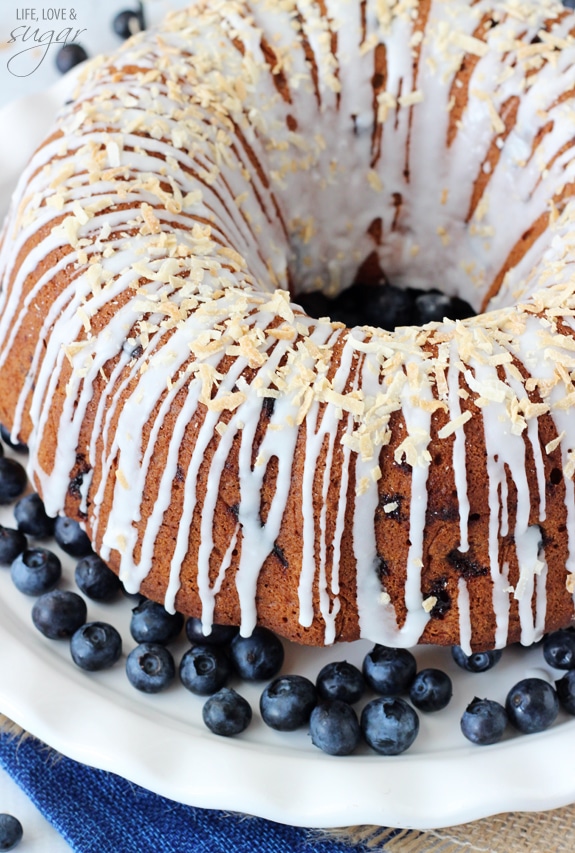 A whole Blueberry Coconut Bundt Cake on a white plate with blueberries