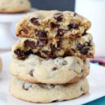 Thick and Chewy Chocolate Chip Cookies on white plate, stacked, one cookie halved