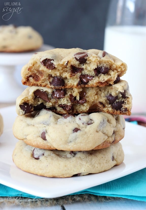 Bakery Style Chocolate Chip Cookies stacked on a plate with two broken in half