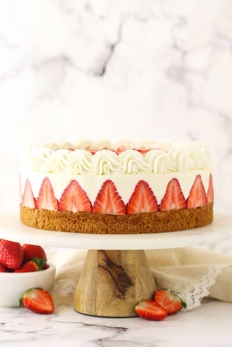 strawberry shortcake cheesecake on marble and wood cake stand