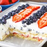 A pan full of strawberry and blueberry icebox cake with a few pieces missing