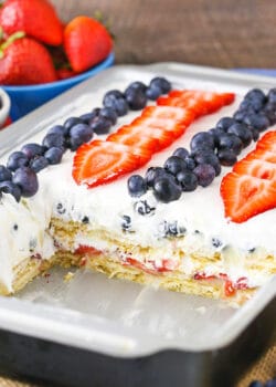 A pan full of strawberry and blueberry icebox cake with a few pieces missing