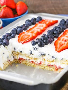 A pan full of strawberry and blueberry icebox cake with a few pieces missing