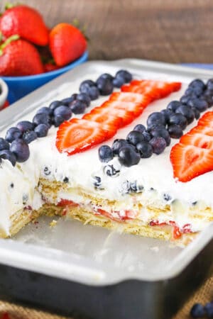 A pan full of strawberry and blueberry icebox cake with a few pieces missing
