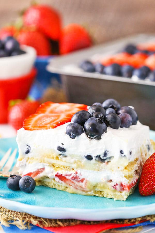 A slice of Strawberry and Blueberry Cheesecake Icebox Cake on a blue plate