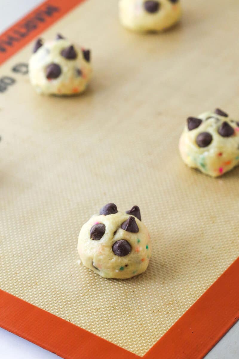 Balls of cake batter chocolate chip cookie dough on a baking sheet