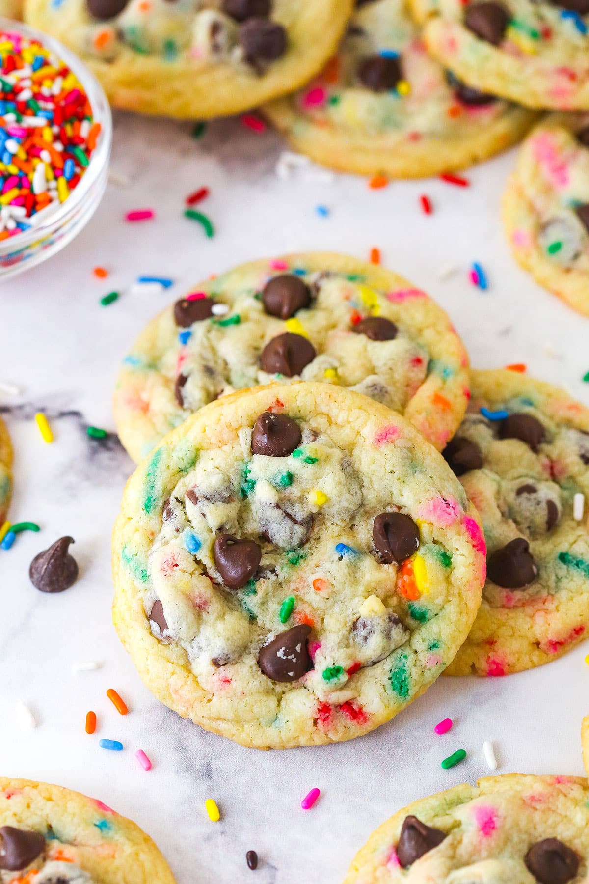 Three funfetti chocolate chip cookies against a marble counter
