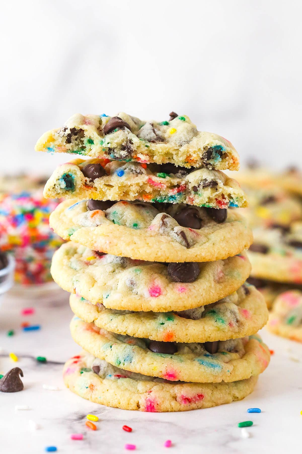 A stack of cake batter chocolate chip cookies with the top one cut in half to show the inside