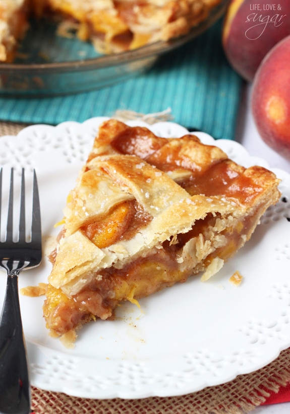 A big slice of Peach Pie with a fork on a white plate