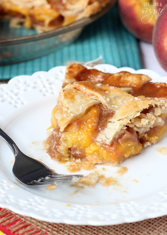 A slice of Peach Pie with a bite missing on a white plate