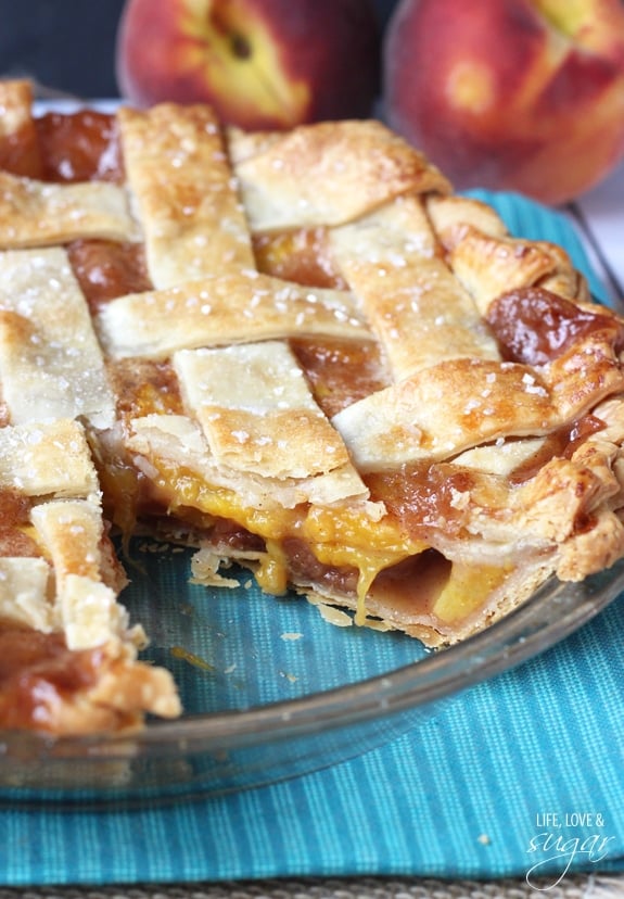 A Peach Pie in a baking dish with a slice missing