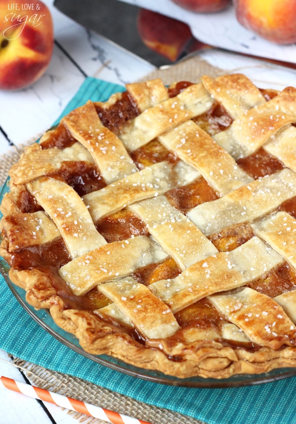 A whole peach pie with a golden crust on a blue cloth