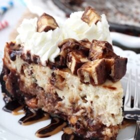 Snickers Cheesecake slice on white plate close up