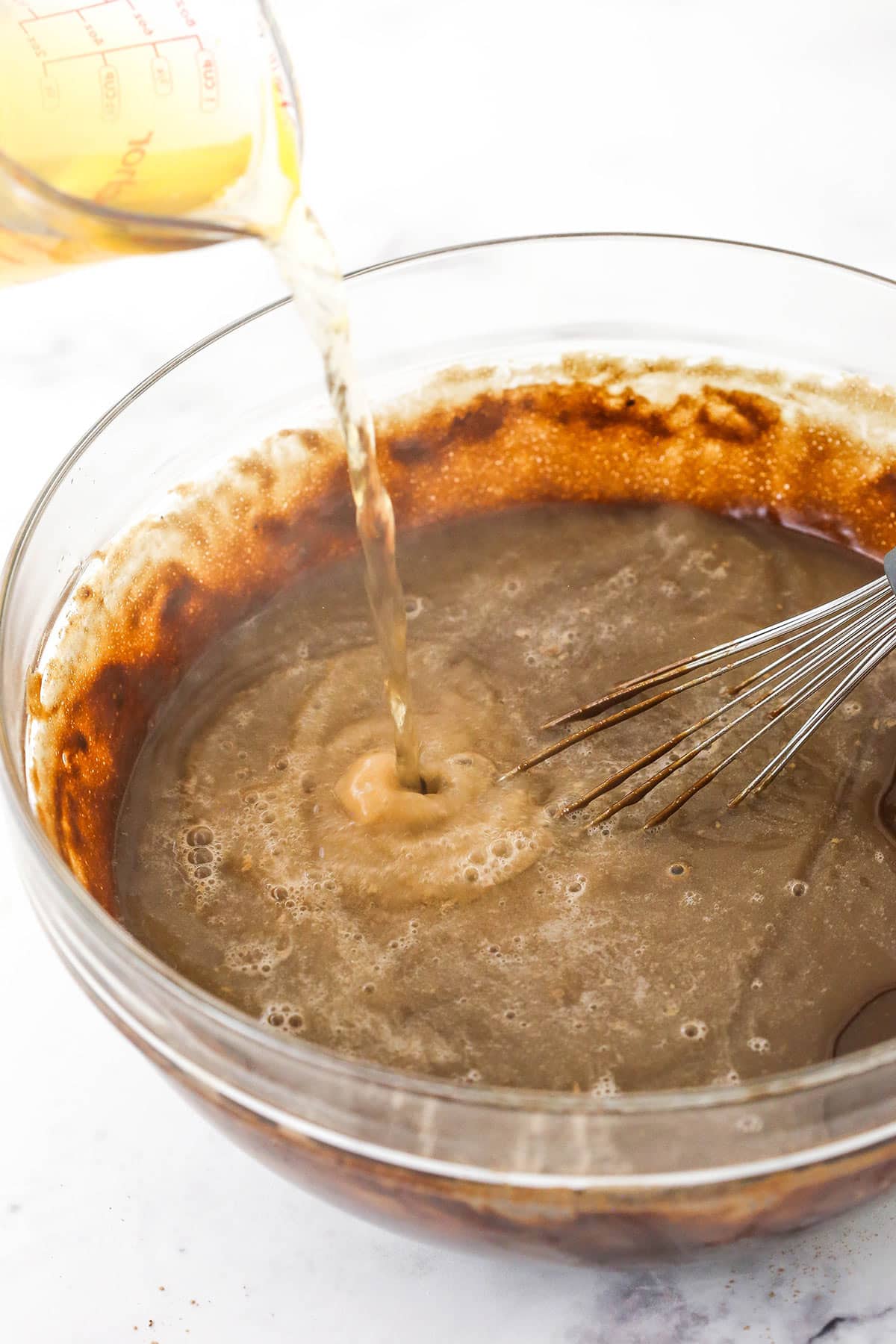 Mixing chocolate cake batter with a whisk in a glass bowl
