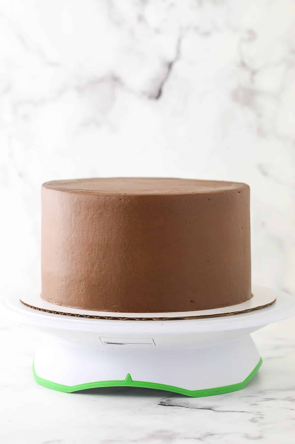 A frosted chocolate cake on a cake stand