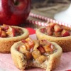 A caramel apple cookie cup on a piece of wax paper with one bite taken out of it