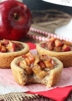 A caramel apple cookie cup on a piece of wax paper with one bite taken out of it