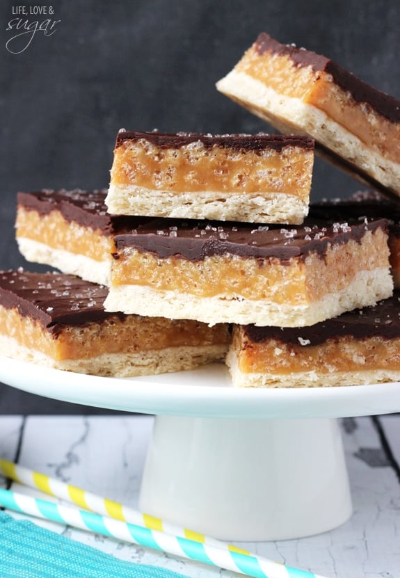 A Bunch of Chocolate Caramel Cookie Bars on Top of a White Cake Stand