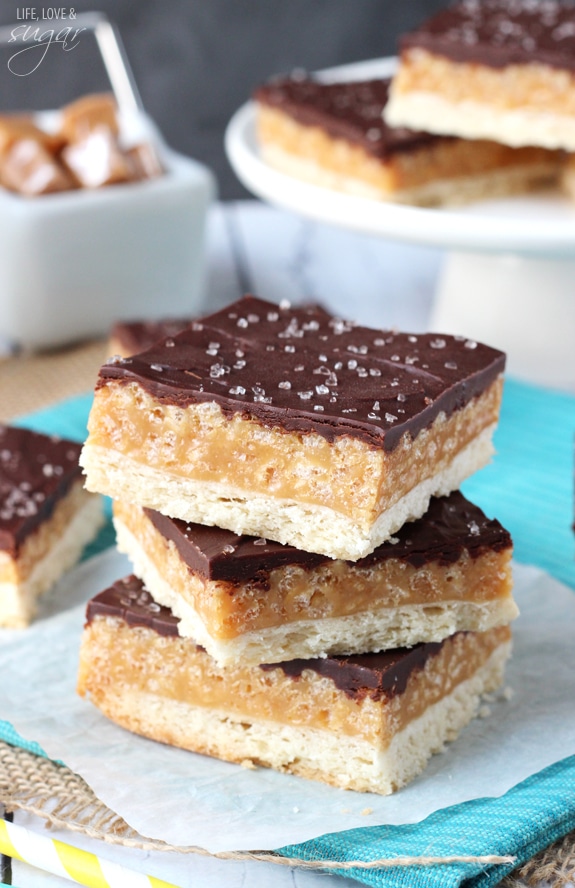 A Pile of Caramel Shortbread Bars Sitting on a Blue Towel Over a Straw Placemat