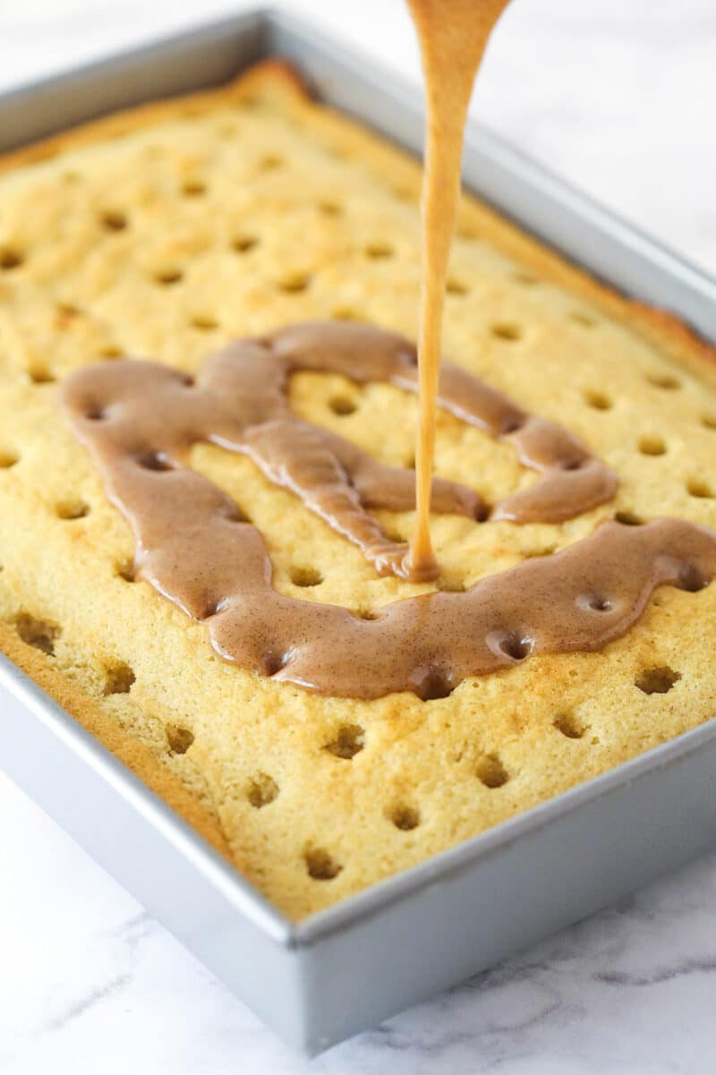 Cinnamon sugar butter being poured over poke cake