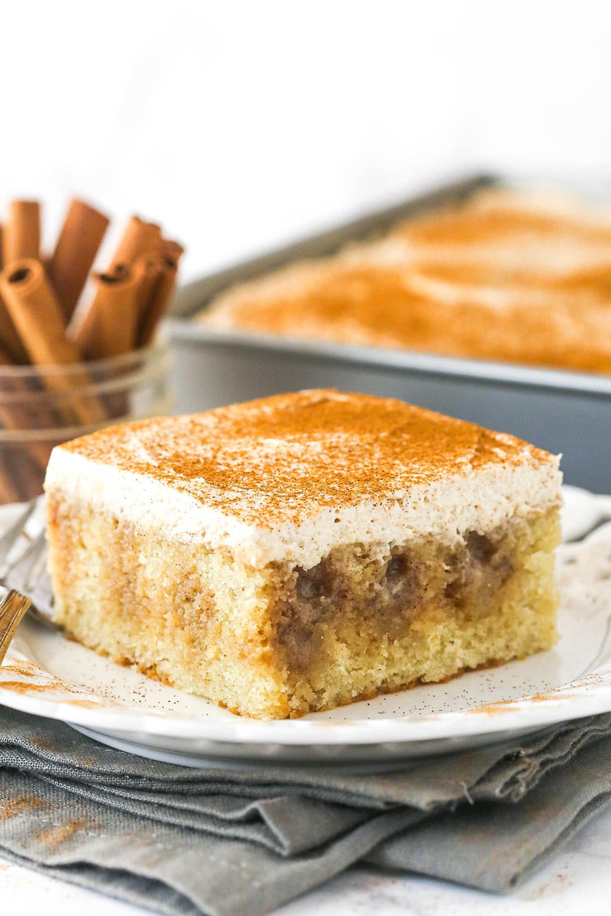 A slice of cinnamon roll poke cake on a white plate