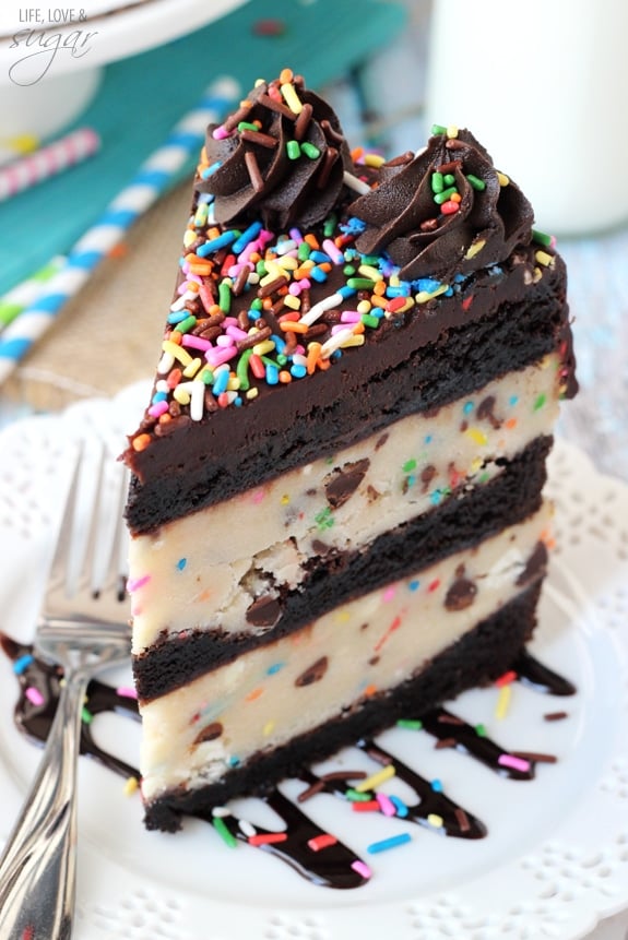 A slice of Funfetti Cake Batter Cookie Dough Brownie Layer Cake on a white plate