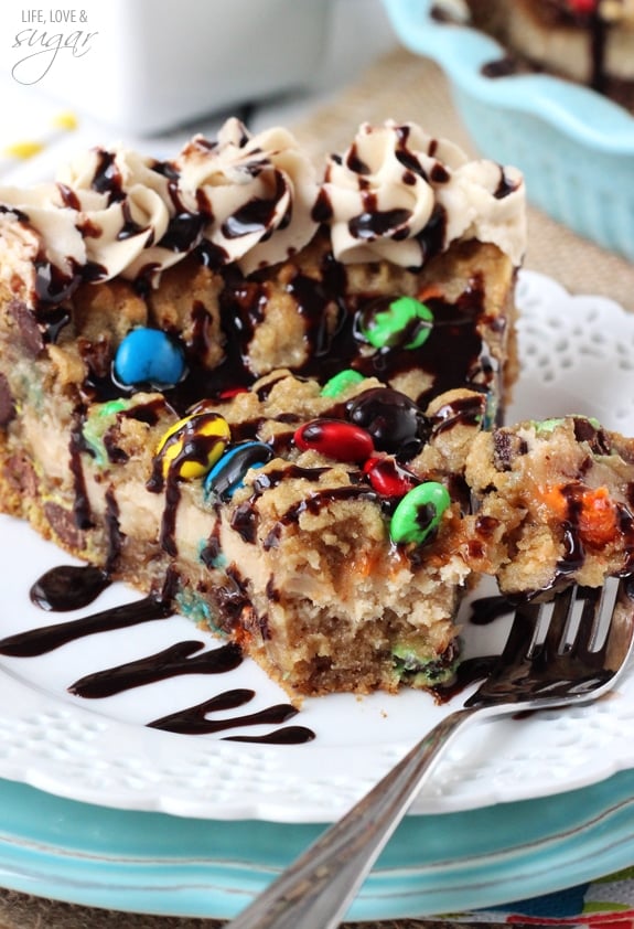 A slice of Monster Cookie Cheesecake Pie on a white plate with a bite on a fork