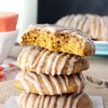A stack of four pumpkin spice cookies on a small piece of wax paper with the top one missing two big bites