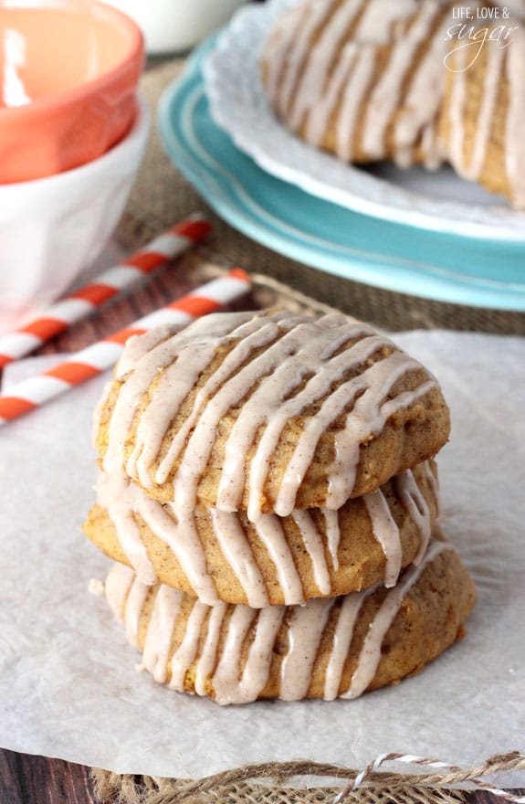 Three glazed cookies stacked on top of each other over a piece of parchment paper on a placemat.