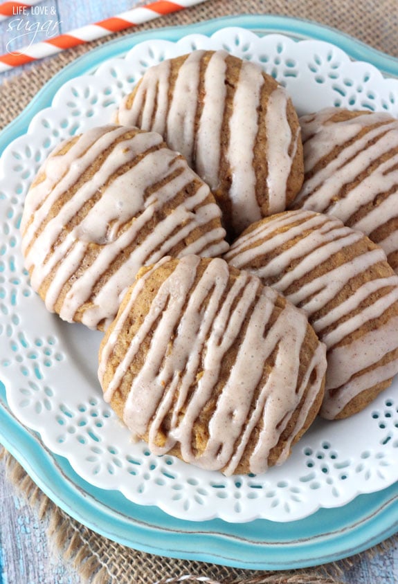 A bird's-eye view of two stacked plates holding five glazed cookies.