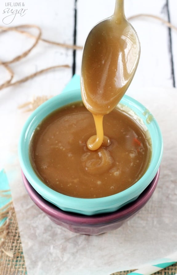 Overhead view of a spoon drizzling caramel sauce into a green and purple stacked bowl set