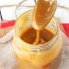 A spoonful of homemade brown sugar caramel sauce being drizzled down into a jar filled with more caramel