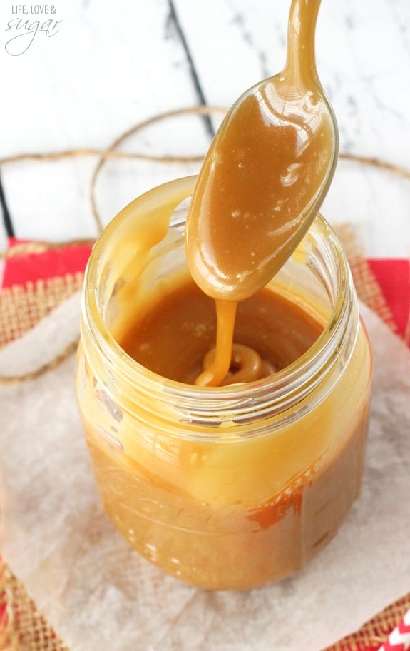 A spoonful of homemade brown sugar caramel sauce being drizzled down into a jar filled with more caramel