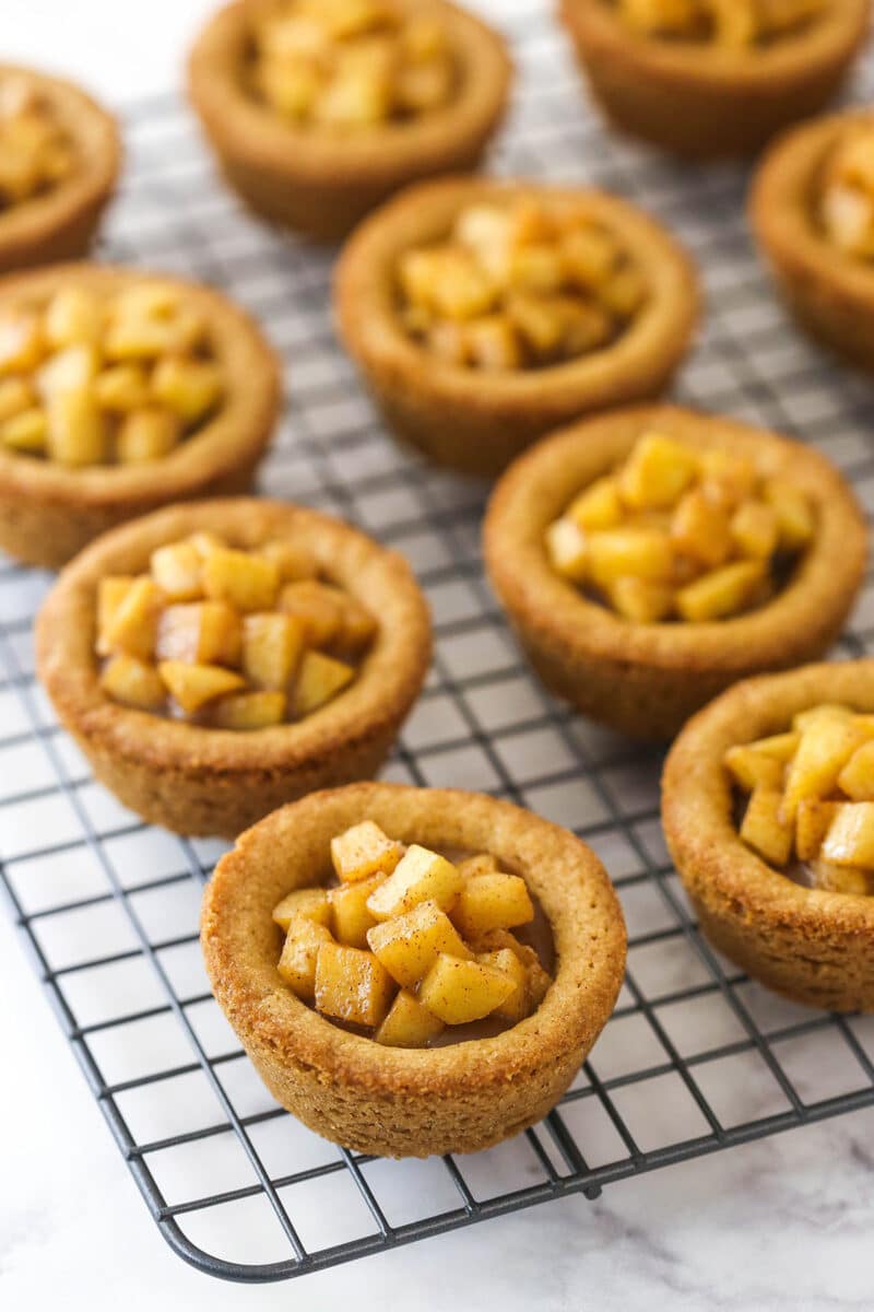 caramel apple cookie cups on cooling rack with caramel and apples added on top
