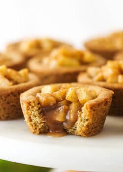 caramel apple cookie cup on marble cake stand with a bite taken out