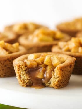 caramel apple cookie cup on marble cake stand with a bite taken out