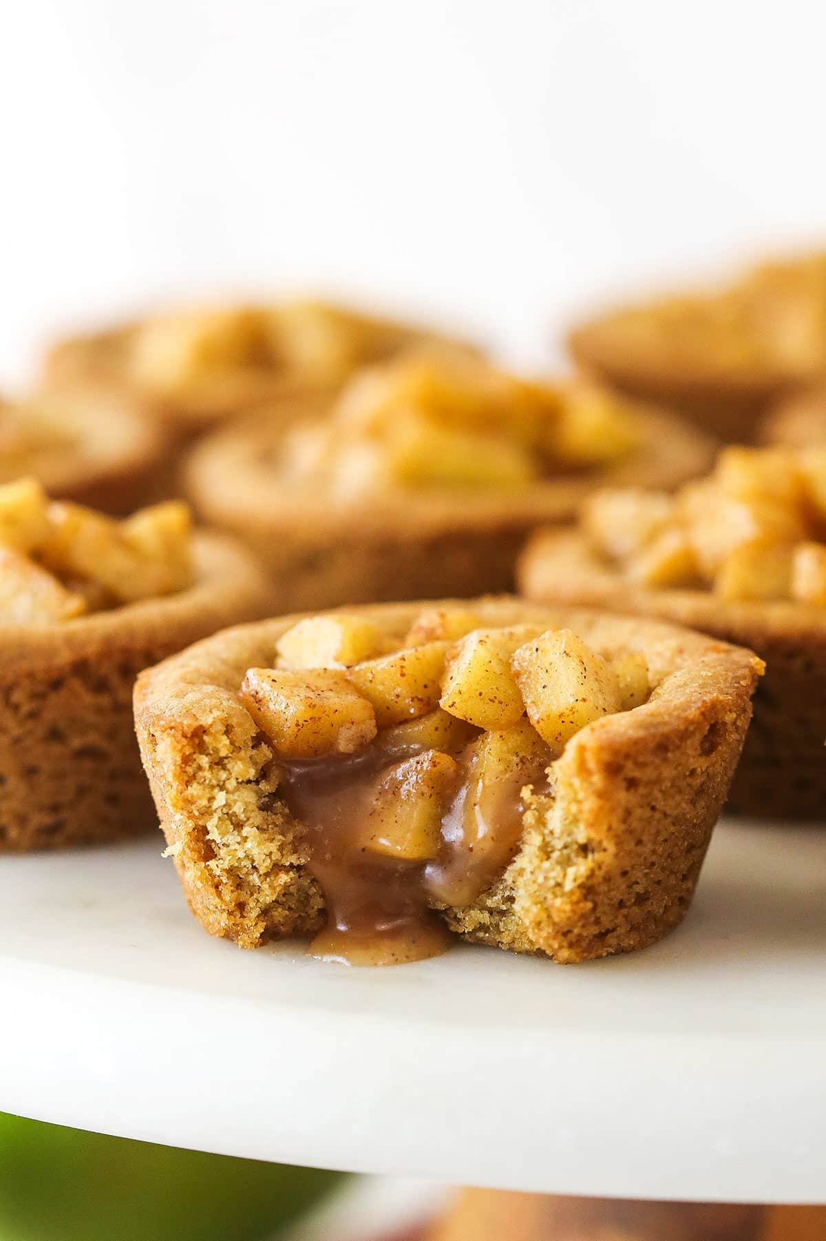 caramel apple cookie cup on marble cake stand with a bite taken out