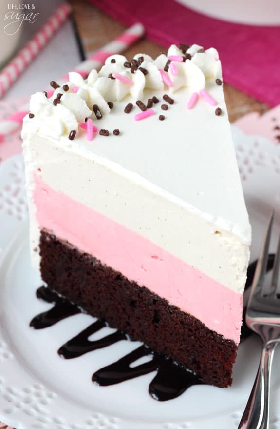 A serving of cake on a plate with two red and pink striped straws right behind it