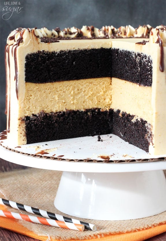 Pumpkin Chocolate Cheesecake Cake on a white cake tray with a couple slices removed