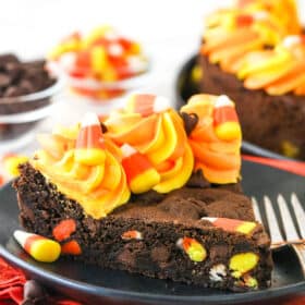 A slice of Candy Corn Chocolate Chip Cookie Cake on a small black plate.