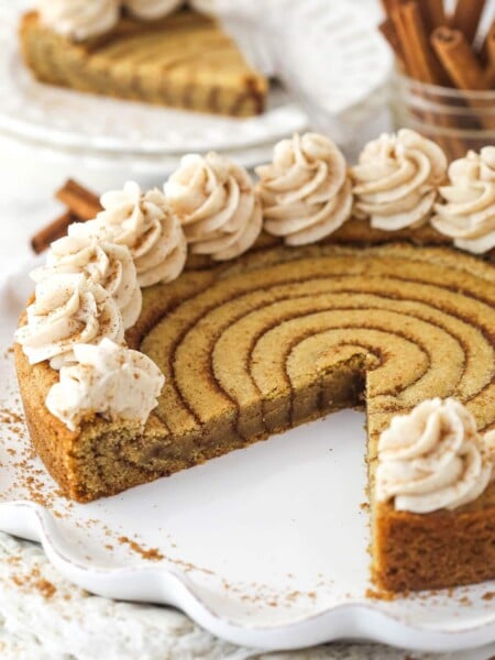 A cinnamon roll cookie cake with a slice missing