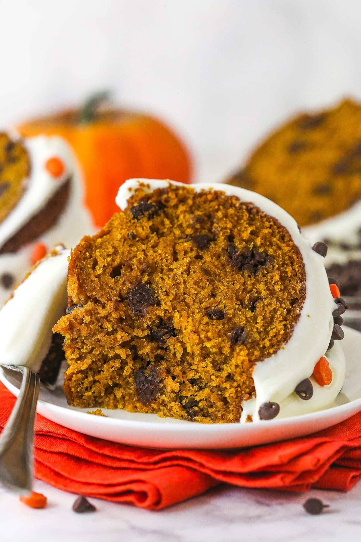 Every bite of this pumpkin chocolate chip bundt cake is moist, perfectly spiced, and dotted with chocolate chips. A slice of pumpkin chocolate chip bundt cake on a white palte