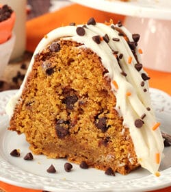 A slice of chocolate chip pumpkin bundt cake with cream cheese frosting and sprinkles on a plate.
