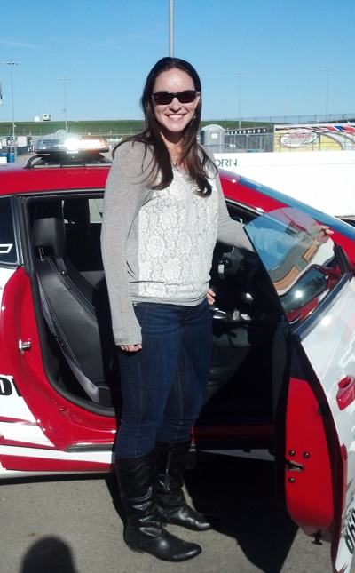 woman standing by a red car at the speedway