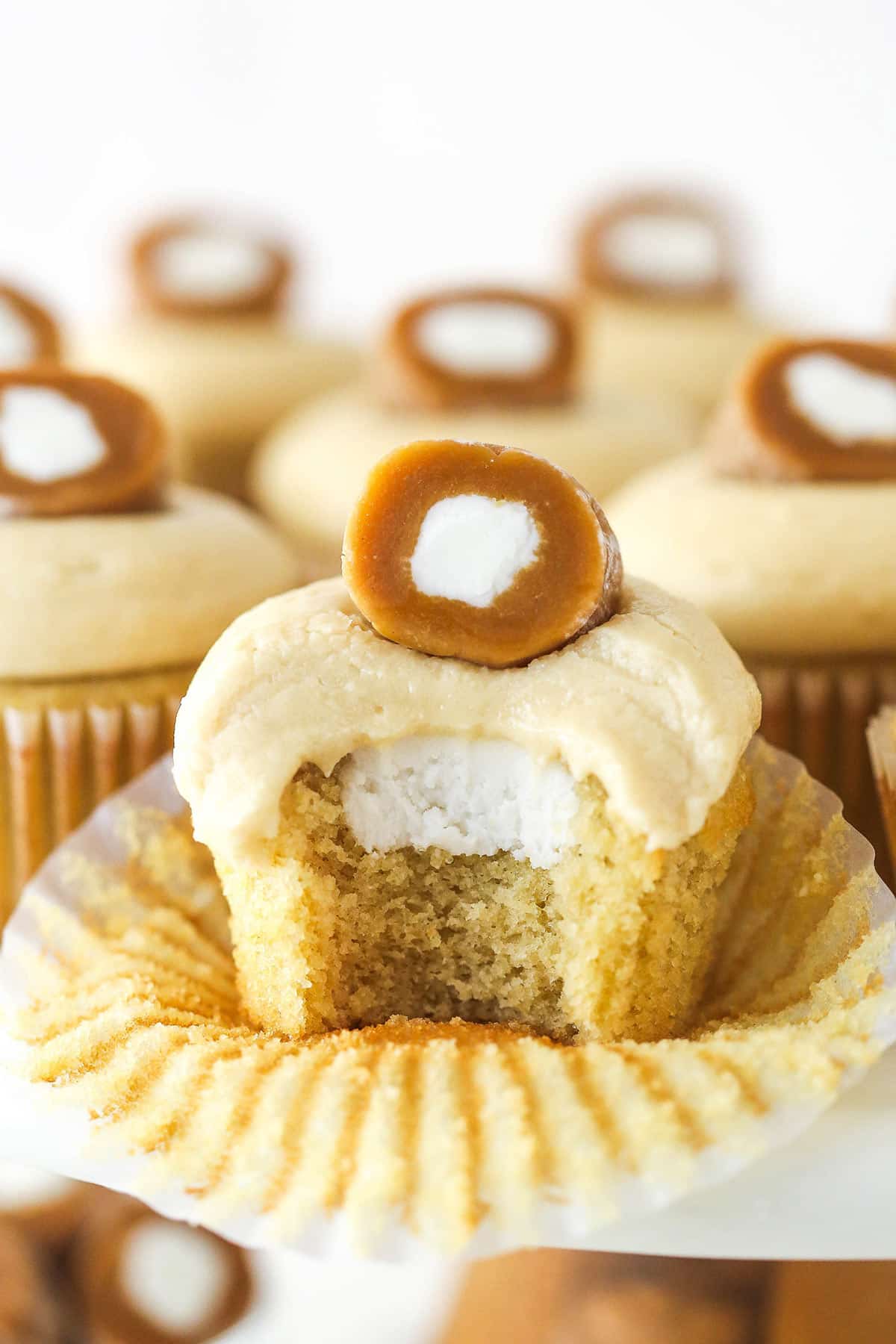With a brown sugar cupcake, cream filling, and caramel buttercream frosting, these Caramel Cream Cupcakes are as sweet and delicious. A caramel cream cupcake with a bite missing