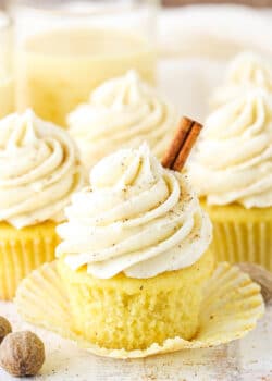 A Christmas eggnog cupcake with the liner removed and a cinnamon stick on top