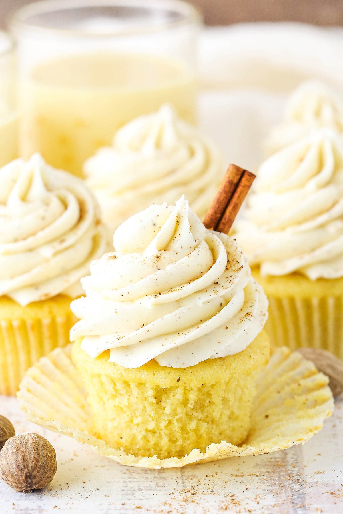 A Christmas eggnog cupcake with the liner removed and a cinnamon stick on top