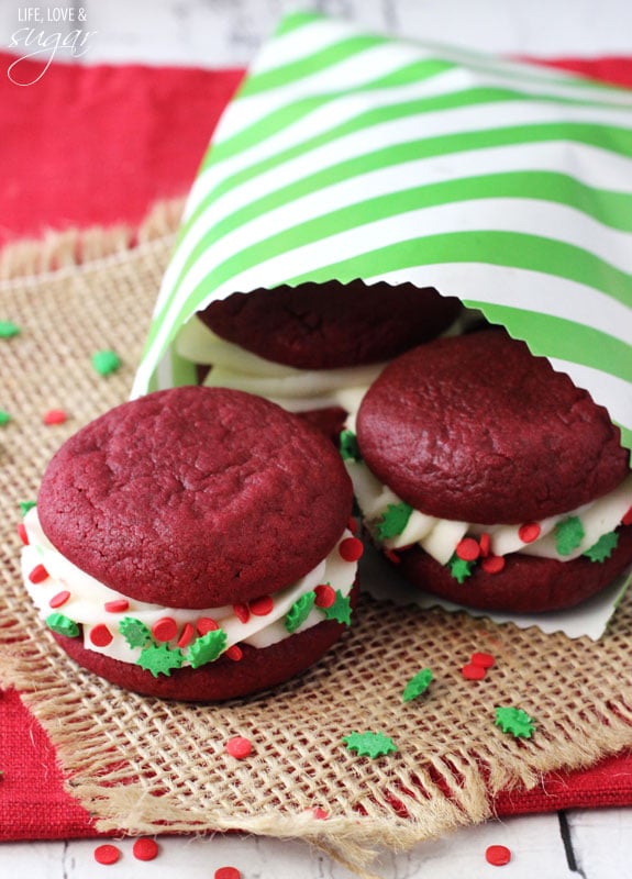 Red Velvet Cookie Sandwiches in a striped paper bag on burlap